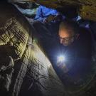 Le chercheur Boris Valentin photographié en train d'observer des gravures préhistoriques dans un abri sous roche 