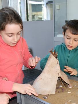 Animation pédagogique consacrée à l'habitat préhistorique. Ici, construction d'une maquette de tente en bois et peau d'animal