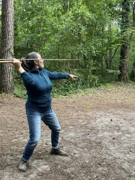 Photographie d'une femme effectuant un tir à l'aide d'une reconstitution de propulseur préhistorique
