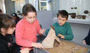 Animation pédagogique consacrée à l'habitat préhistorique. Ici, construction d'une maquette de tente en bois et peau d'animal