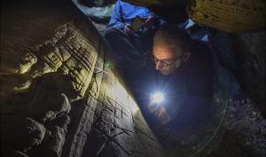 Le chercheur Boris Valentin photographié en train d'observer des gravures préhistoriques dans un abri sous roche 