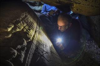 Le chercheur Boris Valentin photographié en train d'observer des gravures préhistoriques dans un abri sous roche 