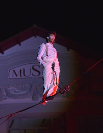 Photographie d'un funambule sur une corde lors d'un spectacle nocturne