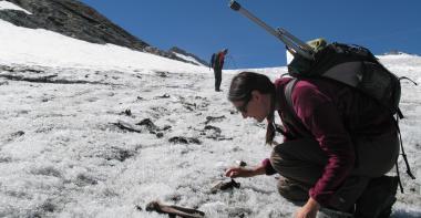 Photo d'une archéologue réalisant un prospection archéologique sur un glacier alpin