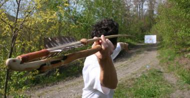 Photo couleur. Un compétiteur de tir préhistorique se prépare à lancer sa sagaie vers une cible.