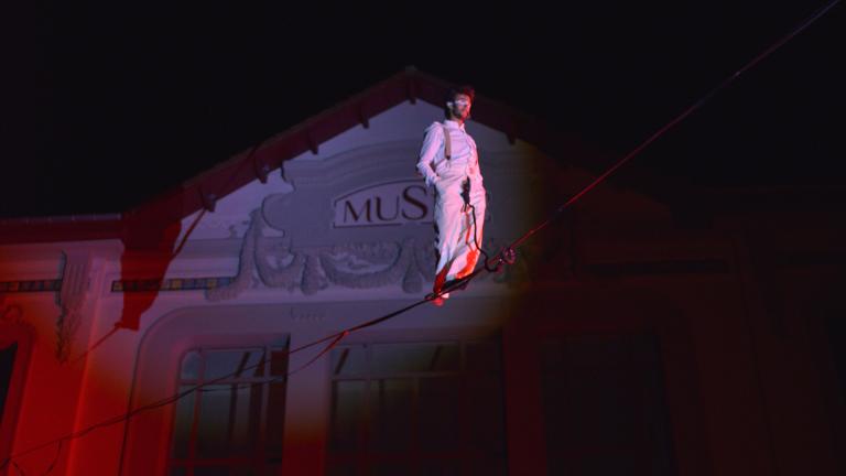 Photographie d'un funambule sur une corde lors d'un spectacle nocturne