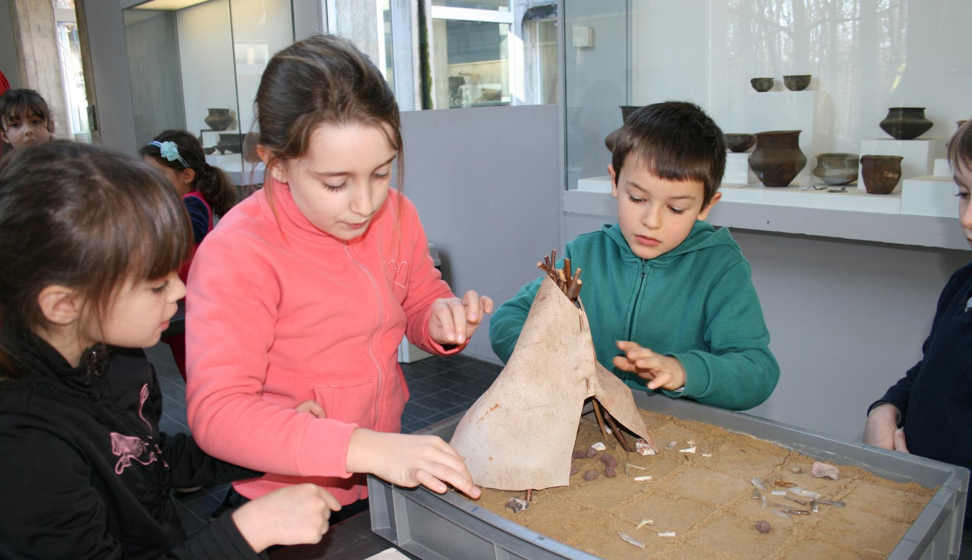 Animation pédagogique consacrée à l'habitat préhistorique. Ici, construction d'une maquette de tente en bois et peau d'animal